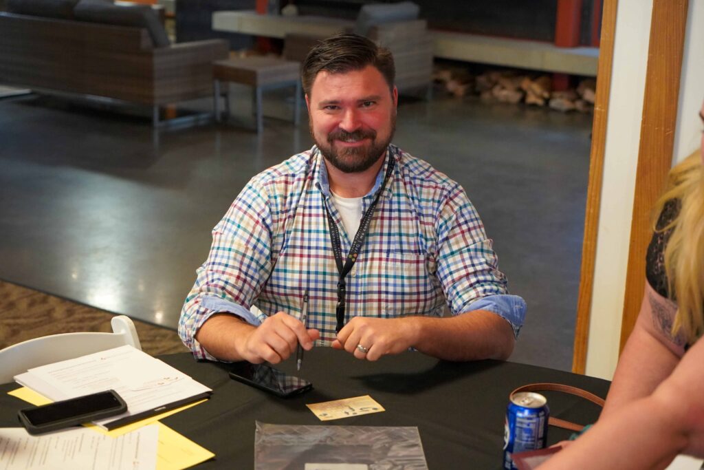 A man sitting at a table smiling for the camera.